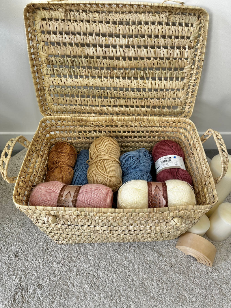 Intérieur d'une malle artisanale en palmier remplie de pelotes de laine colorées