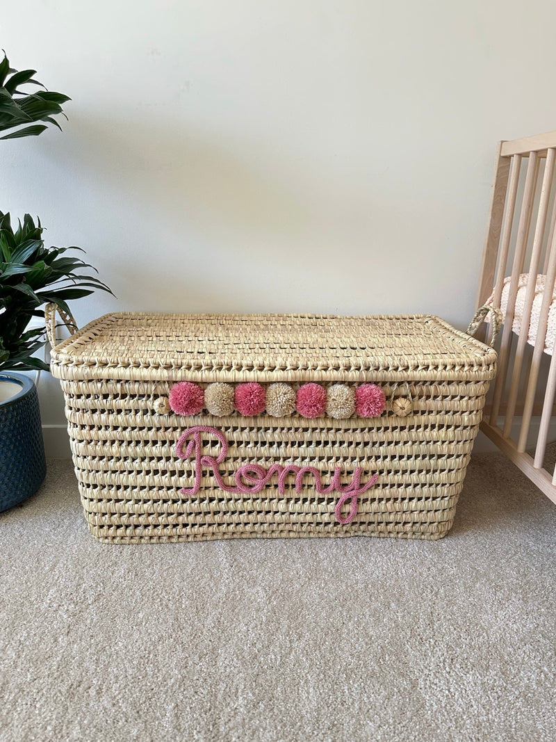 Coffre à jouets personnalisé en osier avec prénom Romy en tricotin rose et pompons roses et beiges
