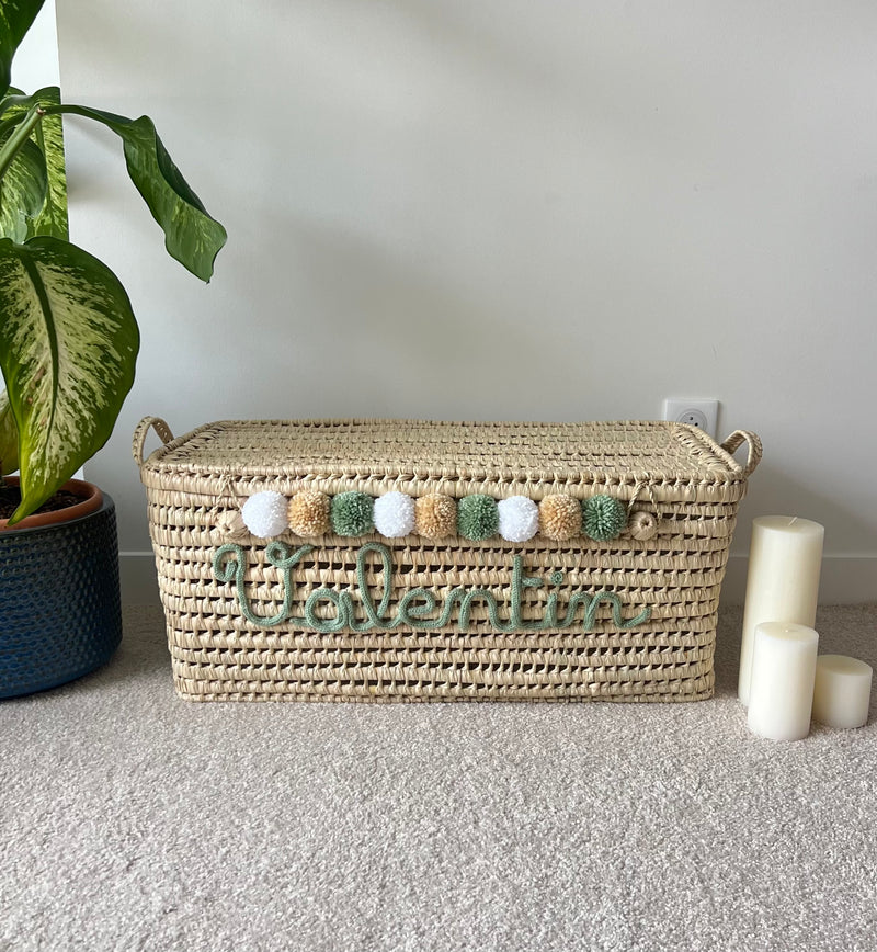 Malle de rangement personnalisée en osier naturel avec prénom en tricotin vert et pompons assortis